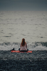 Girl sitting on the seashore and meditating