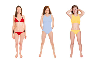 Full length portraits of three gorgeous laughing women wearing colorful swimwear, isolated in front of white studio background