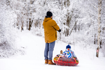 Father and son ride downhill on a Snow tubing