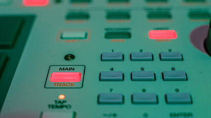 Macro details of a drum machine under colored lights.