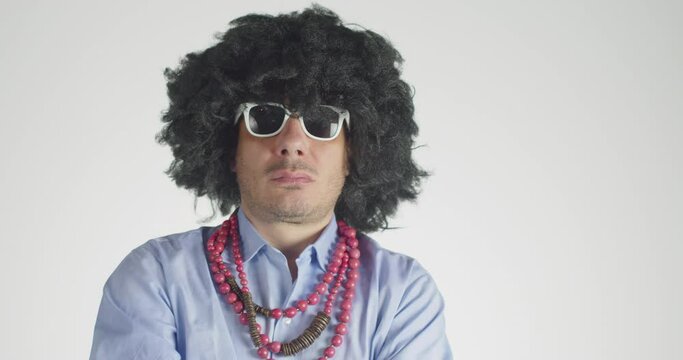 Front view of a curly-haired man wearing white eyeglasses smoking the cigar  and looking at the camera with a menacing gaze  isolated on gray background. 