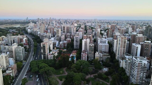 Aerial pan right of Belgrano neighborhood buildings and parks at sunset with Rio de la Plata river in background, Buenos Aires, Argentina