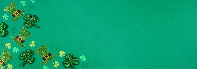 St Patricks Day shamrock and leprechaun hat corner border. Overhead view over a green paper banner background with copy space.