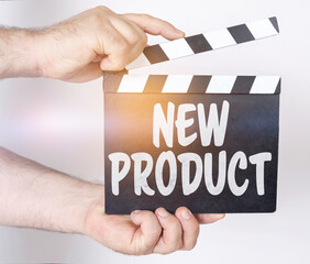 On a white background, a man holds a clapperboard in his hands on which it is written - NEW PRODUCT