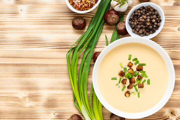 Delicious chestnut soup with croutons and herbs on a wooden table. Top view. Copy space.