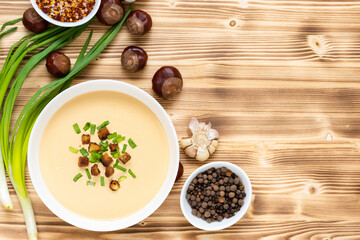 Delicious chestnut soup with croutons and herbs on a wooden table. Top view. Copy space.