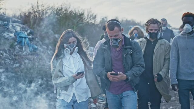 Group of Young Volunteers in Gas Masks Take Care of the Environment While Going Through the Toxic Smoke at Garbage Dump.Worldwide Global Problem of Pollution of Planet.Responsibility by the Future