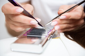 Beautician working on upgrading silk eyelashes in a beauty studio.