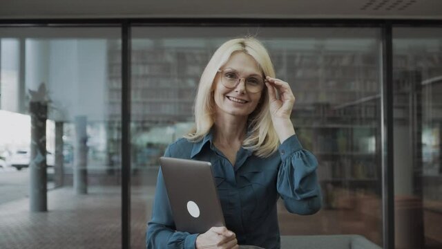 beautiful blond businesswoman with glasses standing with arms crossed in the offic.
