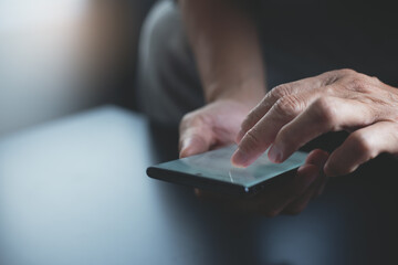 Man hand using mobile phone, finger touching on light screen with dark background