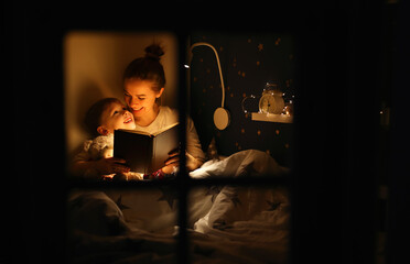 Cheerful mother and son cuddling and reading fairytale