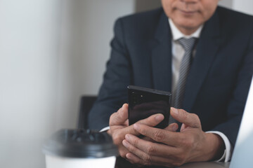 Close up business man using mobile phone lookig at screen during working in modern office
