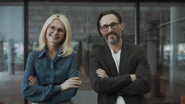 Smiling happy business partners or co-workers, with a middle-aged man and woman at office, looking at the camera