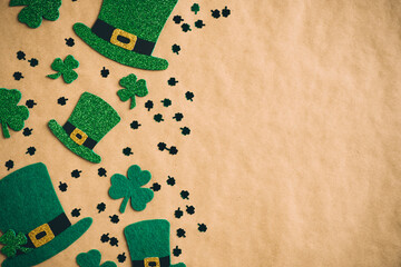 Happy Saint Patrick's Day concept. Flat lay composition with green hats and shamrock clover leaves on kraft paper background. Vintage, retro style.