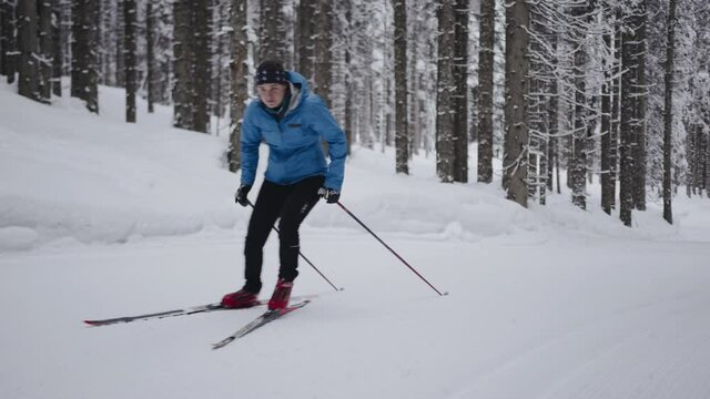 Professional athlethe cross country skier running on skis trough the frozeen forest covered in snow