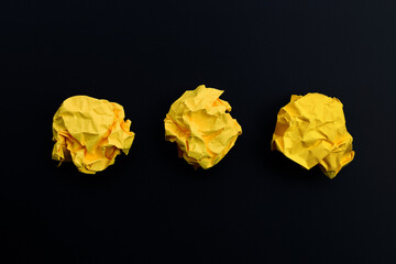 Crumpled yellow paper balls on dark background.