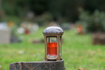 metal grave lantern on a marble pedestal in front of graves in blurred background