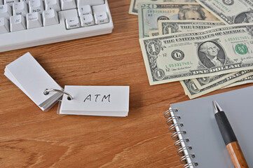 On the desk were bills, a notebook, and a sticky note with the word ATM written on it. It was an abbreviation for the financial term at the money.