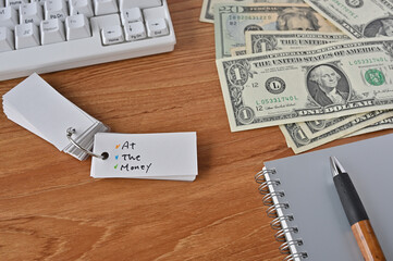 On the desk there were bills, a keyboard, and a word book with the word at the money written on it.