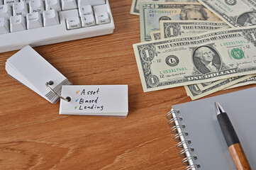 On the desk there were bills, a keyboard, and a word book with the word Asset Based Lending written on it.