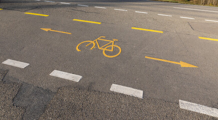 bicycle lane with yellow bicycle symbol on the concrete road during the day, without people