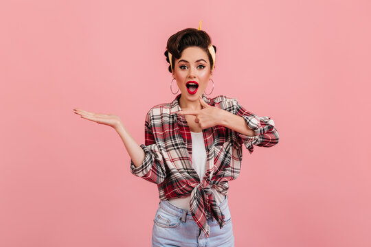 Magnificent pinup girl pointing with finger. Glad attractive woman in checkered shirt posing with hand up.