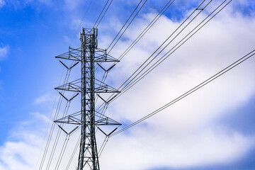 High voltage electricity tower; white clouds and blue sky background
