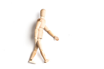 Wooden Mannequin on top of white table as if its walking and standing.