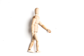 Wooden Mannequin on top of white table as if its walking and standing.