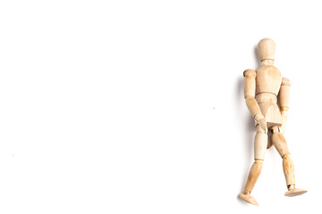 Wooden Mannequin on top of white table as if its walking and standing.