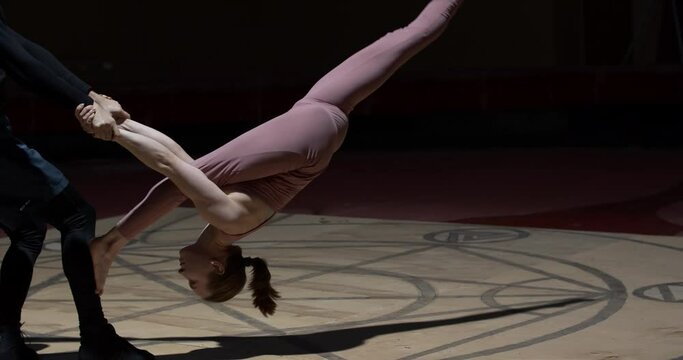 Young woman is doing a split while a man is holding her, duo gymnastics, 4k