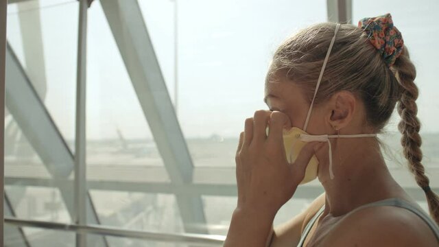 Woman caucasian at Suvarnabhumi Airport with wearing protective medical mask on head against background of plane. Concept health virus protection coronavirus epidemic sars-cov-2 covid-19 2019-ncov.