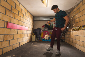Young caucasian man playing with a soccer ball at the garage