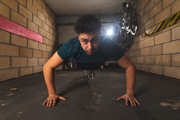 Fototapeta na wymiar Young caucasian man doing push-ups at the garage 
