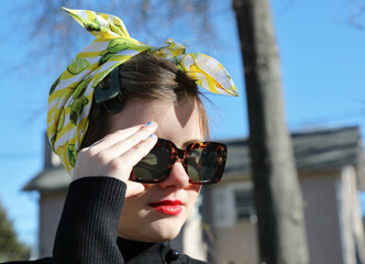 Teenager girl in square sunglasses and yellow bandana.