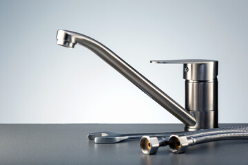 Plumbing service. Faucet and tools on dark countertop.