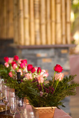 Red and pink roses on a table in vases as a wedding decoration
