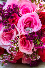 Pink and purple rose bouquet with wedding rings inside the flower