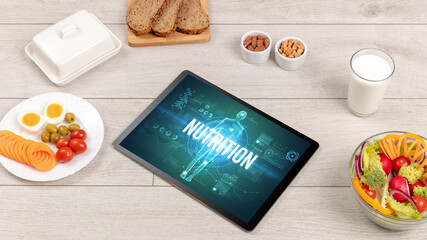 NUTRITION concept in tablet with fruits, top view