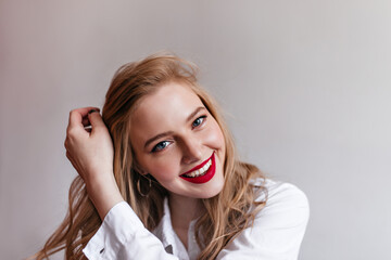 Joyful blonde girl with red lips looking at camera. Smiling european young woman posing in white shirt.