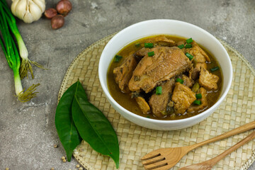 Semur Ayam Tahu, Indonesian traditional food made with chicken, tofu, spices, soy sauce and palm sugar. Grey grainy background, copy space for text. 