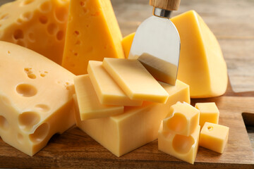 Different sorts of cheese and knife on wooden board, closeup