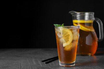 Delicious iced tea on grey table against black background, space for text