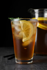 Delicious iced tea on grey table against black background, closeup