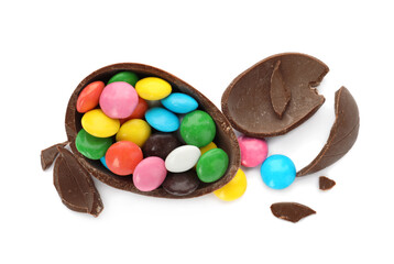 Broken chocolate egg with colorful candies on white background