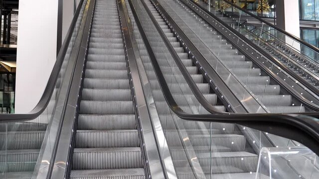 Empty working outdoor escalator built next to big modern building and leading to business premises.