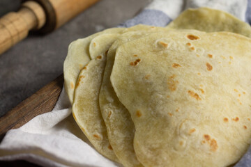 Homemade Kulit Kebab or Tortilla wrap on blue white napkin on wooden rustic tray. 
