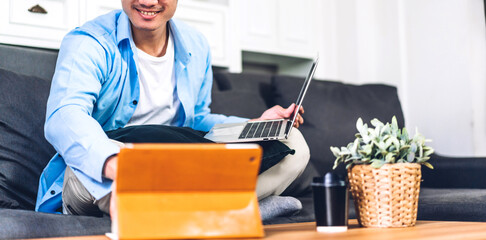 Young smiling asian man using laptop computer working and video conference online meeting with colleagues at home.Young creative man use tablet.work from home concept