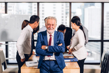 Senior businessman look at camara with laptop and discussing strategy with new startup project.Creative business people planning and brainstorm with document report in modern workloft.Teamwork concept