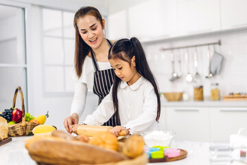 Portrait of enjoy happy love asian family mother and little asian girl daughter child having fun cooking together with baking cookies and cake ingredients on table in kitchen